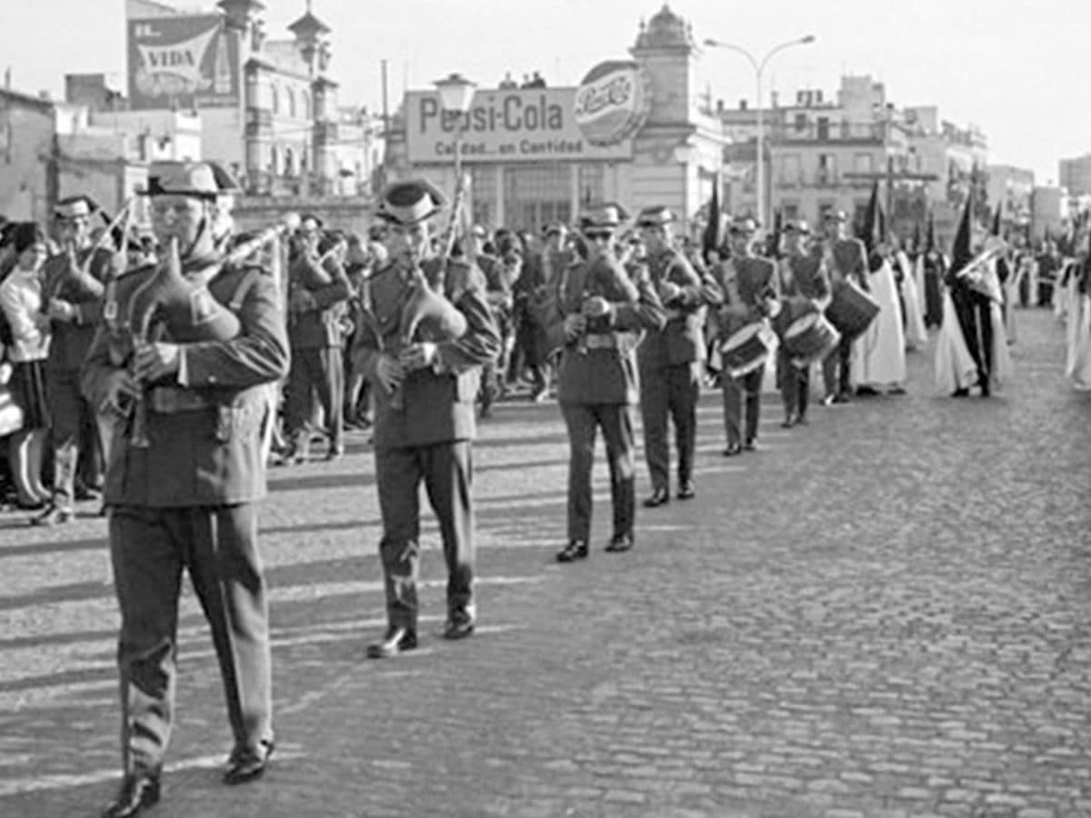 Tarde del Viernes Santo. Delante de la Cruz de Guía de la Hermandad del Cachorro la Agrupación Musical de la Segunda Unidad Móvil de la Guardia Civil. Además de cornetas y tambores, incorporaba trompetas, saxofones, trombones, platillos y gaitas