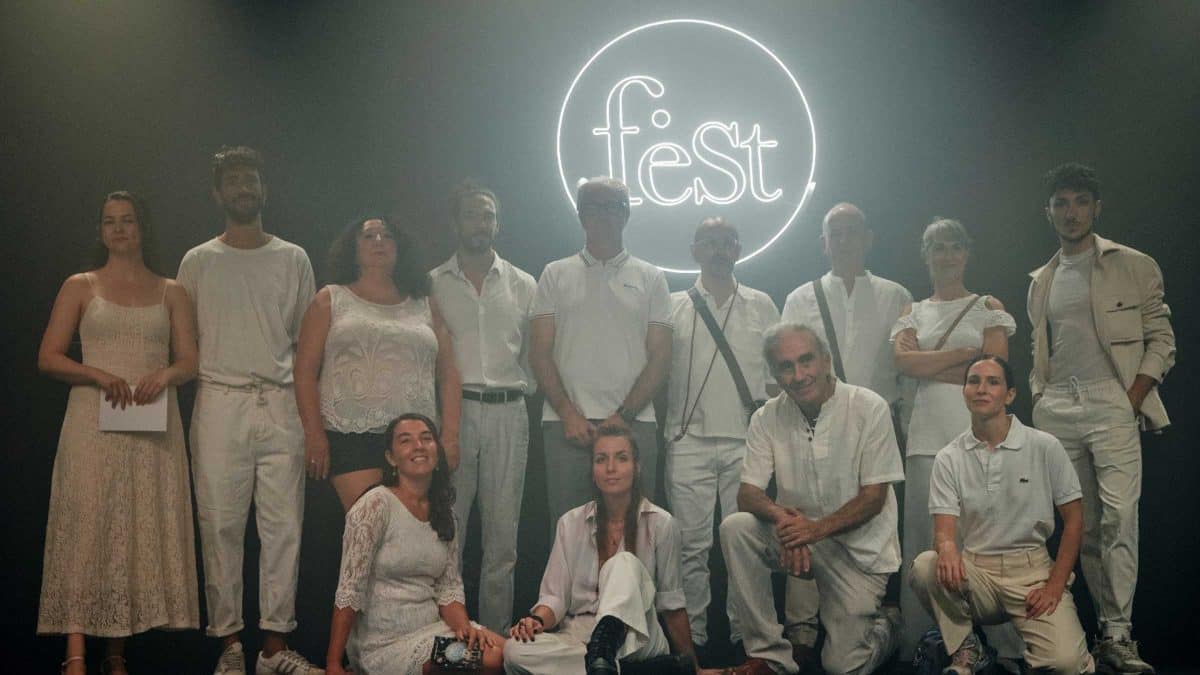 Varios participantes posan frente al cartel del festival