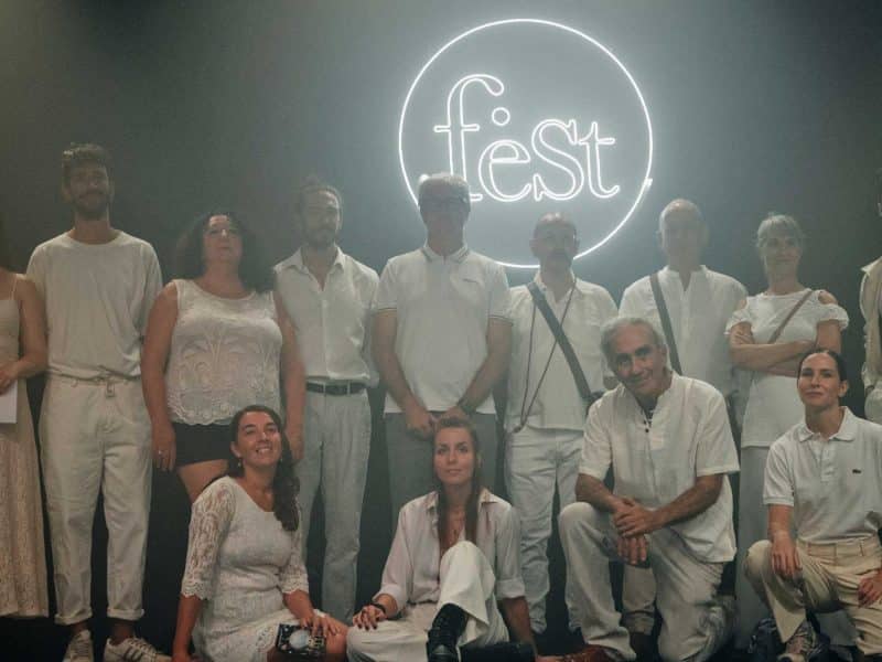Varios participantes posan frente al cartel del festival