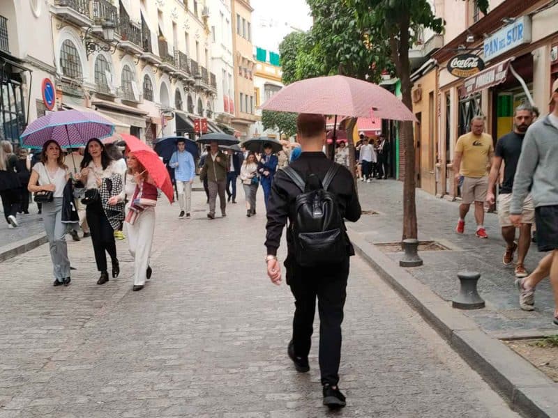 Personas caminando bajo la lluvia en la calle Arfe de Sevilla. A.A.D