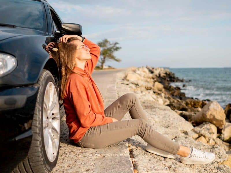 Mujer apoyada en un coche