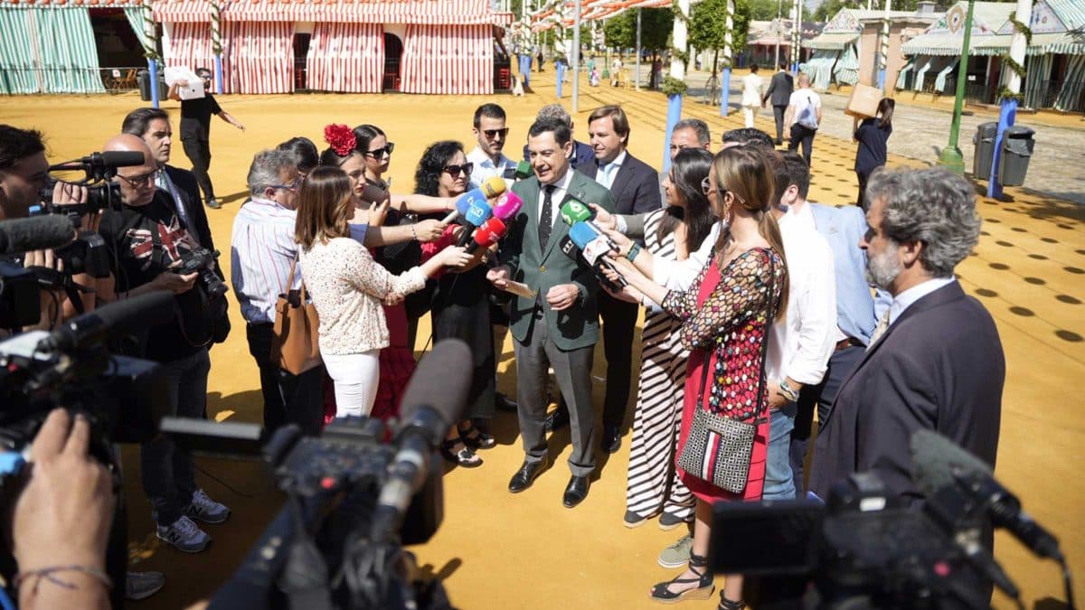 Juanma Moreno siendo preguntado por periodistas en la Feria de Sevilla