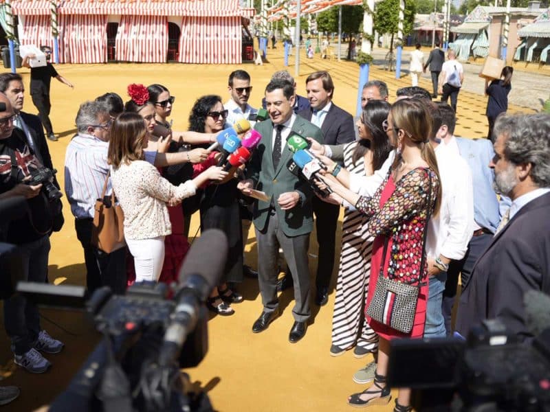 Juanma Moreno siendo preguntado por periodistas en la Feria de Sevilla