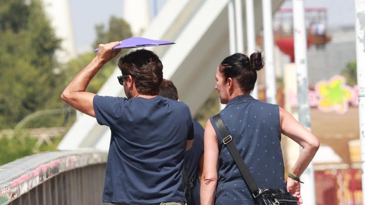 Imagen de archivo de dos personas paseando bajo el Sol en el Puente de la Barqueta. EP
