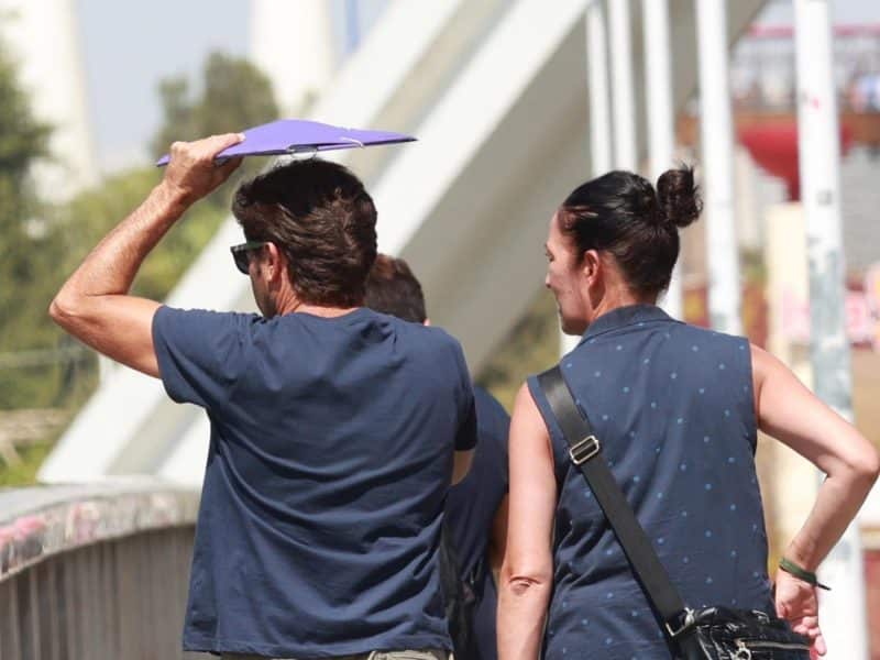 Imagen de archivo de dos personas paseando bajo el Sol en el Puente de la Barqueta. EP