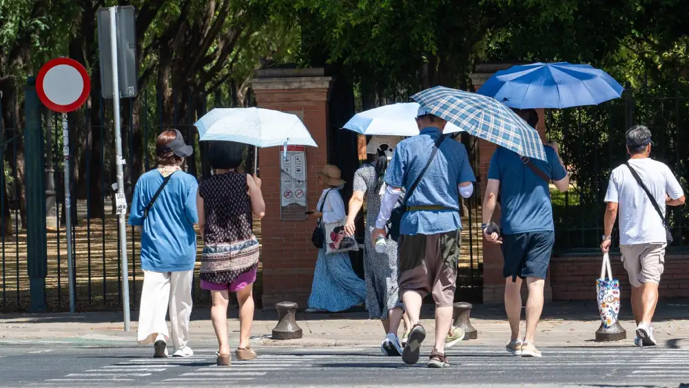 Imágenes de personas caminando con sombrillas por las calles de la capital hispalense (imagen de archivo). - Francisco J. Olmo - Europa Press