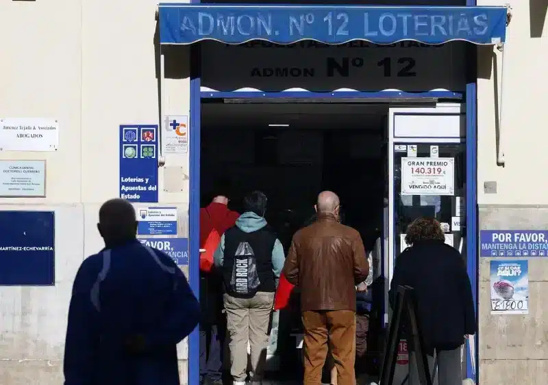 Varias personas hacen cola para comprar décimos de la Lotería de Navidad en Málaga - Álex Zea - Europa Press