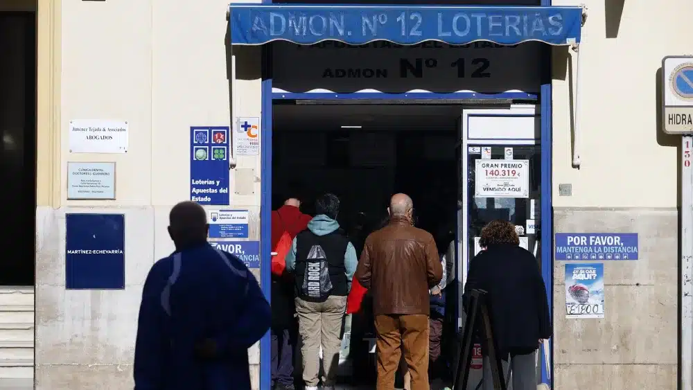 Varias personas hacen cola para comprar décimos de la Lotería de Navidad en Málaga - Álex Zea - Europa Press