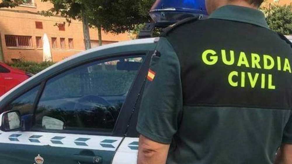 Agente de la Guardia Civil ante un coche patrulla - Guardia Civil