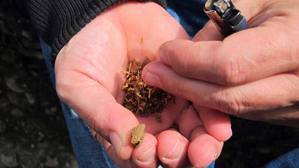 Un joven elaborando un porro de hachís - Europa Press