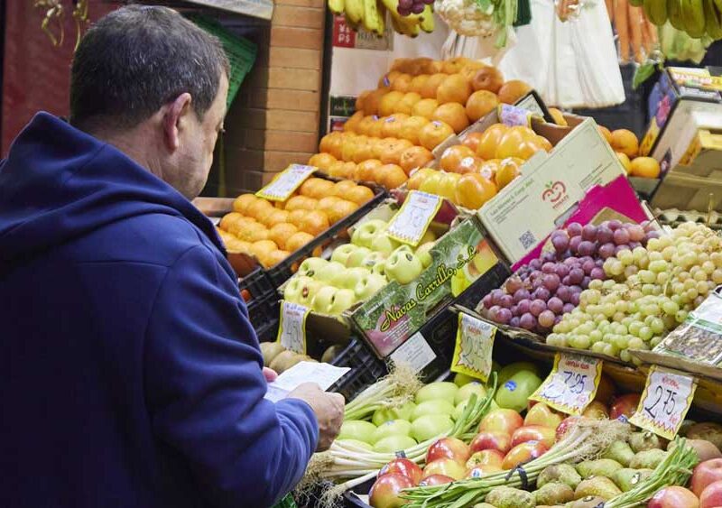 Un señor con un listado de productos en un puesto del mercado de abastos - Joaquin Corchero / Europa Press