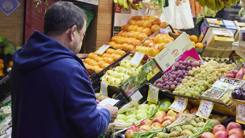 Un señor con un listado de productos en un puesto del mercado de abastos - Joaquin Corchero / Europa Press