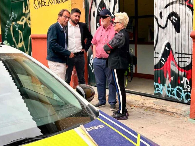 Ismael Sánchez, con representantes de la asociación Mácula Retina, con un patrullero de la Policía Local en un primer plano.- IU