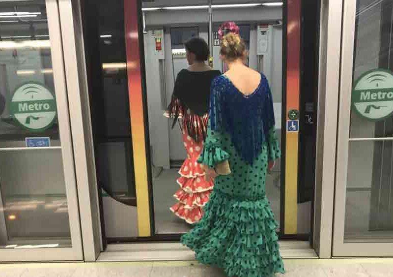 Mujeres vestidas de flamenca acceden al interior de uno de los vagones del metro. - Metro de Sevilla