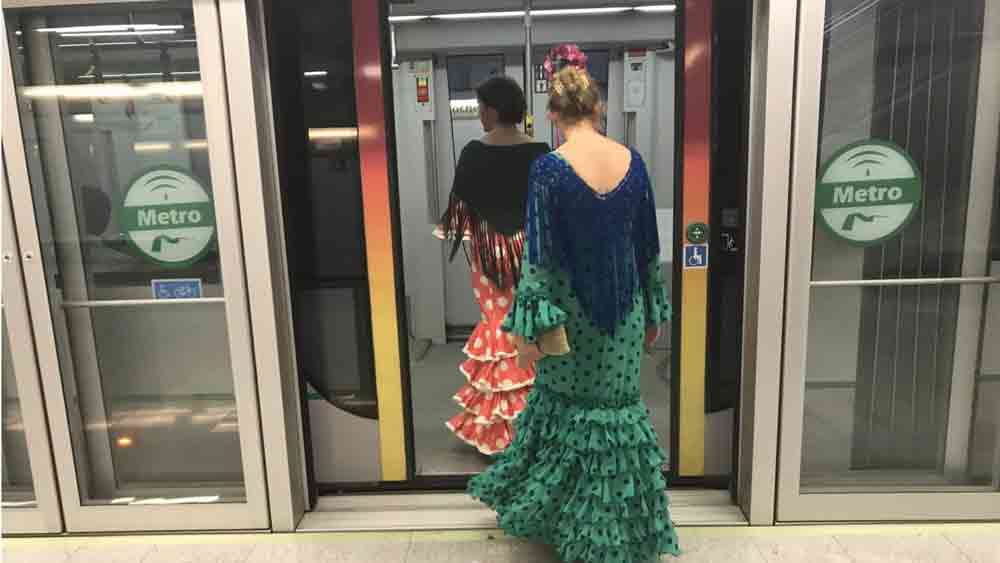 Mujeres vestidas de flamenca acceden al interior de uno de los vagones del metro. - Metro de Sevilla